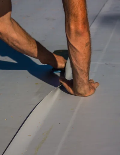 A man is laying down a white tarp on a roof.